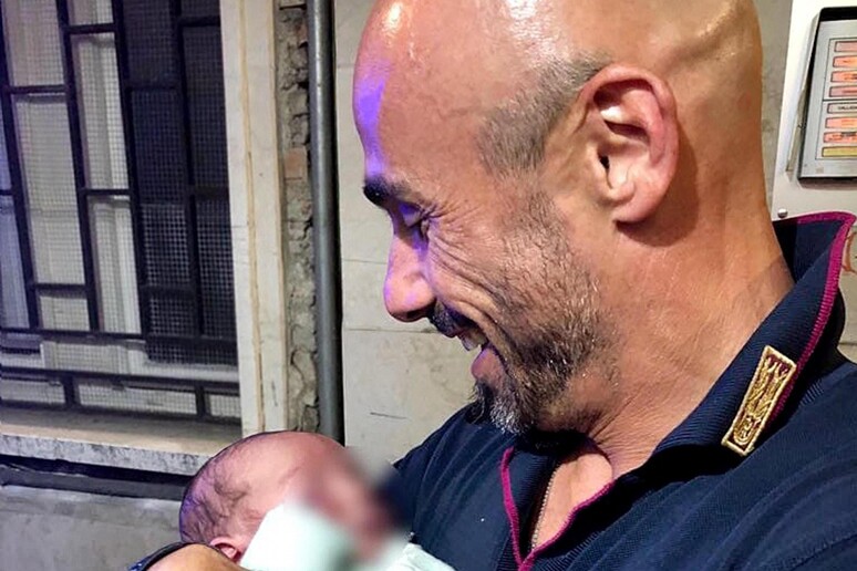 L 'agente di polizia Antonio Matrone tiene in braccio il neonato abbandonato in centro città a Brescia e ritrovato da un residente, 21 maggio 2018 - RIPRODUZIONE RISERVATA