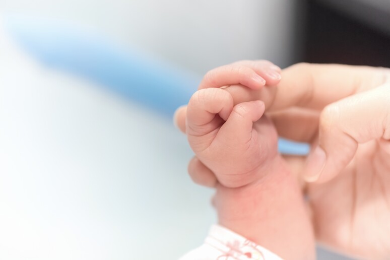 La manina di una neonata che stringe il dito della mamma (archivio) - RIPRODUZIONE RISERVATA