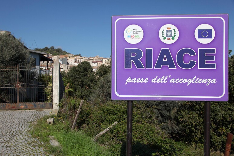 Uno dei vecchi cartelli a Riace (Reggio Calabria), quando era sindaco Lucano - RIPRODUZIONE RISERVATA