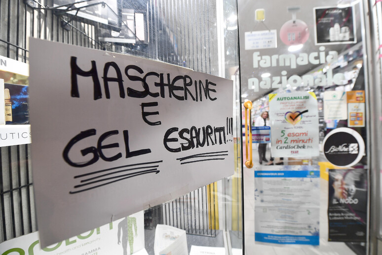 Un cartello esposto sulla vetrina esterna di una Farmacia genovese, che segnala l 'esaurimento di gel  disifettanti e mascherine di protezione per il viso (archivio) - RIPRODUZIONE RISERVATA