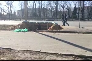 Ucraina, un uomo scava una trincea in una strada principale di Kiev (ANSA)