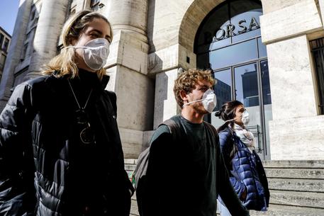 Persone con mascherine davanti all'ingresso della Borsa a Milano © ANSA