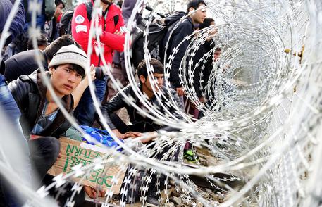 Profughi afghani a ridosso della barriera di filo spinato al confine fra la Grecia e la Macedonia del Nord © ANSA 