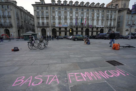 Alcune donne, rappresentanti del gruppo Non una di meno, scrivono con i gessetti colorati in piazza Castello, a Torino, i nomi delle donne assassinate © ANSA
