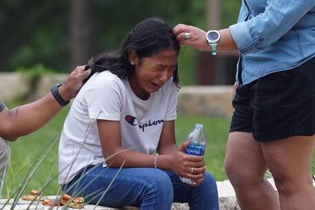 Una ragazza in lacrime riceve conforto © AFP