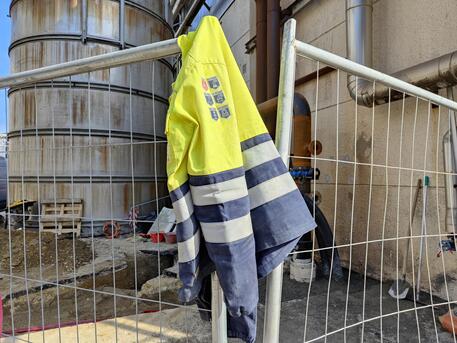 Una giacca da lavoro appesa al cancello di un cantiere © ANSA
