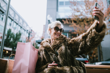 Una donna soddisfatta degli acquisti si fa un selfie, foto iStock.