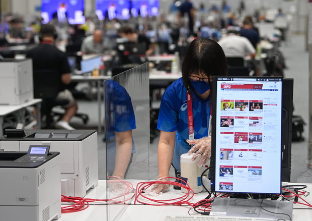 An employe disinfects a workstation at the Olympic Media Center (foto: EPA)