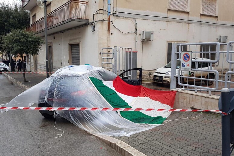 I colleghi del militare ucciso a Cagnano Varano intervenuti sul posto hanno coperto l 'auto di servizio con una bandiera tricolore, 13 aprile 2019 - RIPRODUZIONE RISERVATA