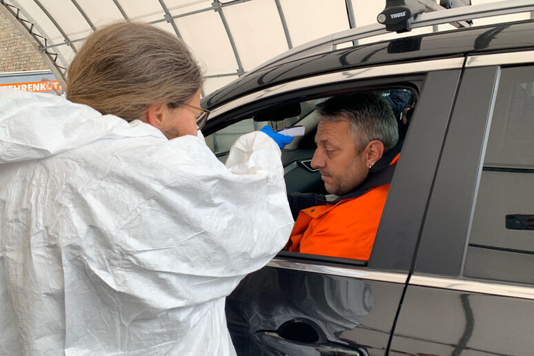 Un medico austriaco in equipaggiamento protettivo controlla la temperatura di un automobilista al  passo del Brennero - RIPRODUZIONE RISERVATA