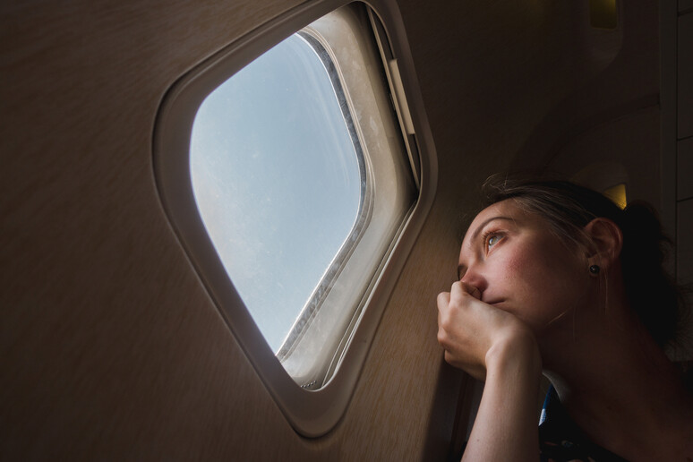 Una donna guarda dal finestrino di un aereo. foto iStock. - RIPRODUZIONE RISERVATA