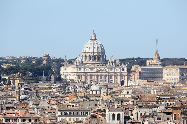 La cupola della basilica di San Pietro tra i tetti di Roma in una foto di archivio - RIPRODUZIONE RISERVATA
